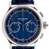 Close-up of a luxury Patek Philippe chronograph watch with a blue dial, two subdials, and a silver case on a dark strap