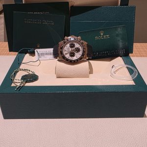 Rolex wristwatch displayed in an open green presentation box with manuals and cards nearby.