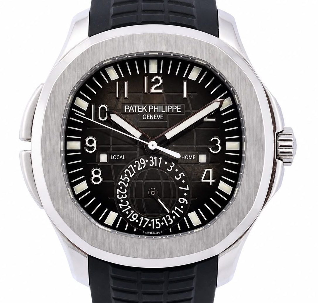 Patek Philippe Geneva steel wristwatch with a black dial, large numerals, and a black rubber strap.