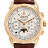 Gold-tone Patek Philippe wristwatch with white dial and brown leather strap; day, date, month, and moon-phase complications visible on the face.